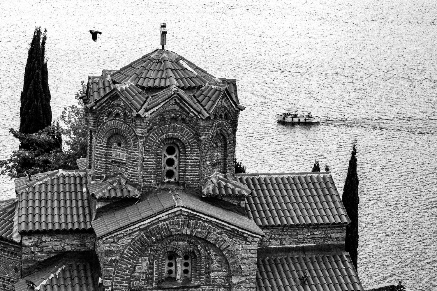 Church of Saint Jovan the Theologian at Kaneo overlooking Lake Ohrid in Ohrid, North Macedonia, with a boat and a bird in the background.