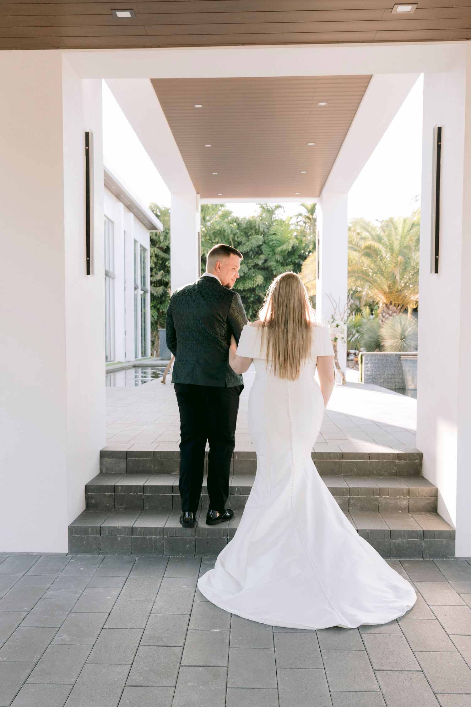A wedding scene in an elegant covered walkway with white columns and gray stone flooring.