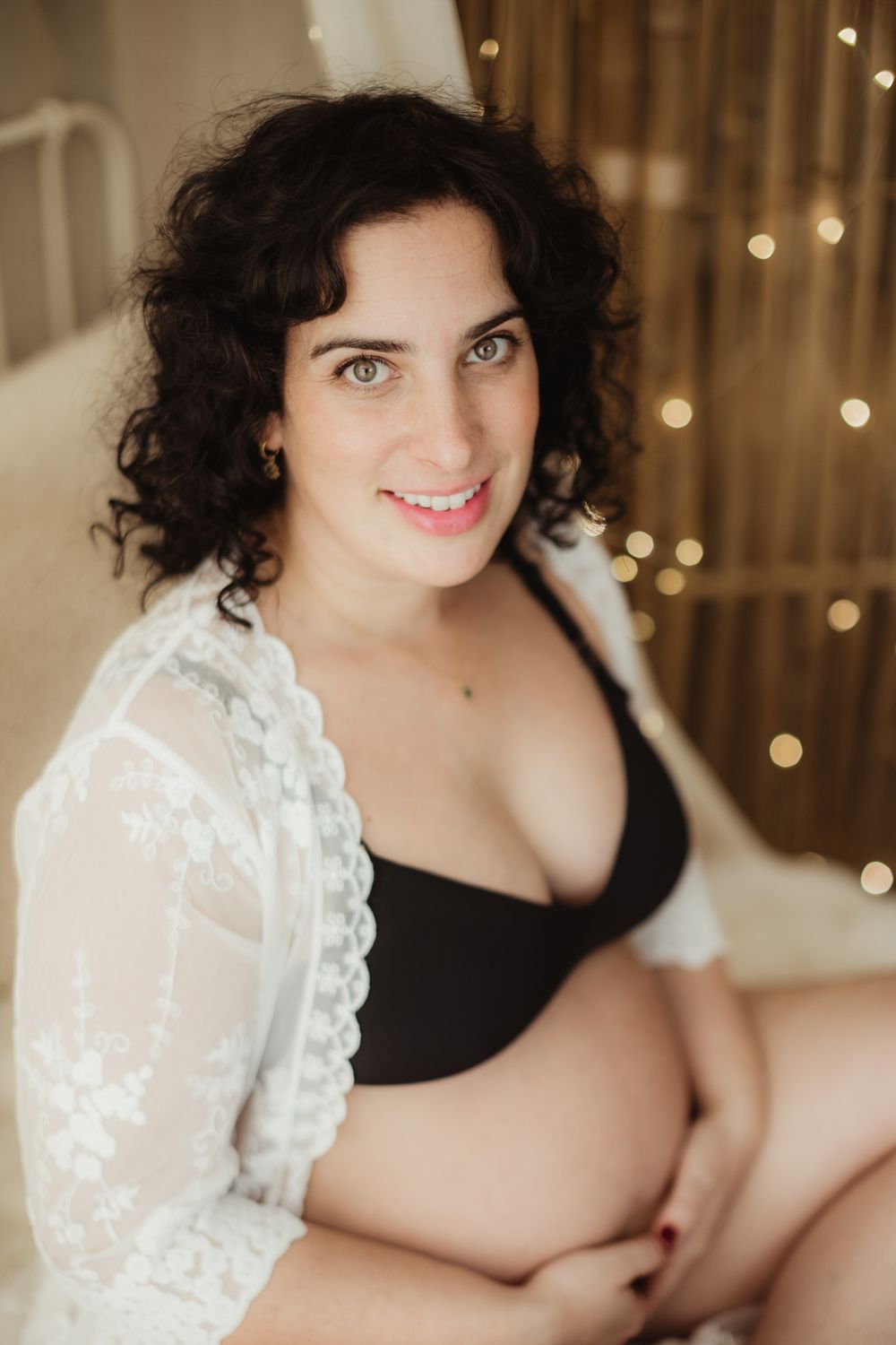 Intimate boudoir portrait with black lingerie and white lace in warm lighting with bokeh background.