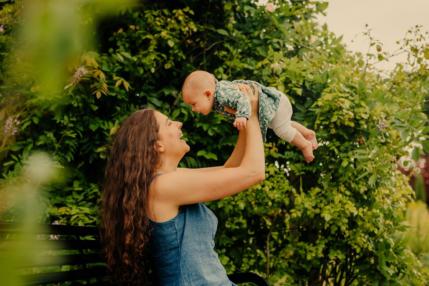 A young couple hold their laughing baby in a park