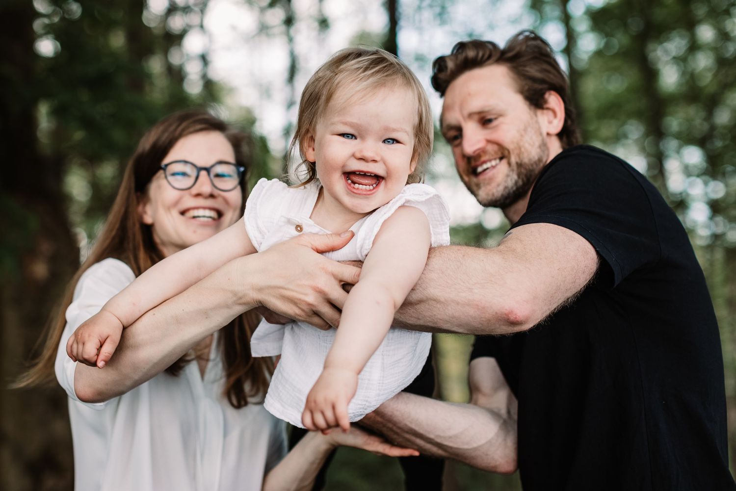 A joyful family moment captured outdoors against a forest backdrop.