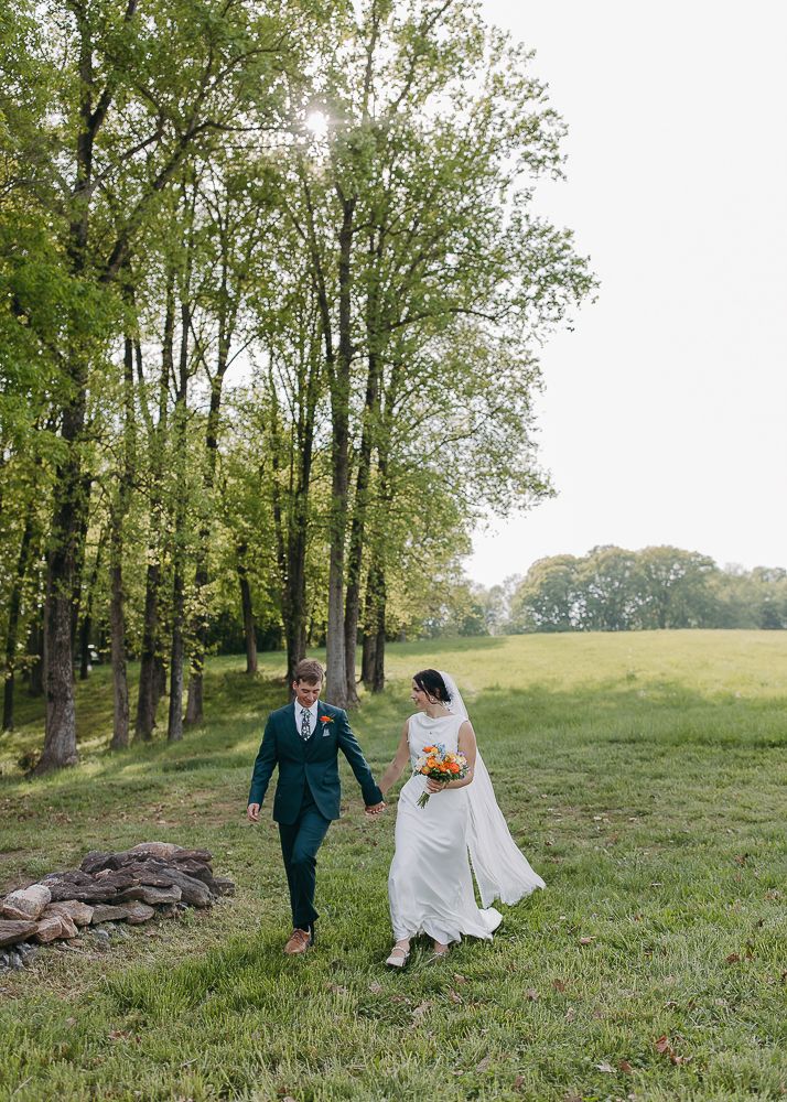 Couple walking together across a scenic hillside meadow on their wedding day.