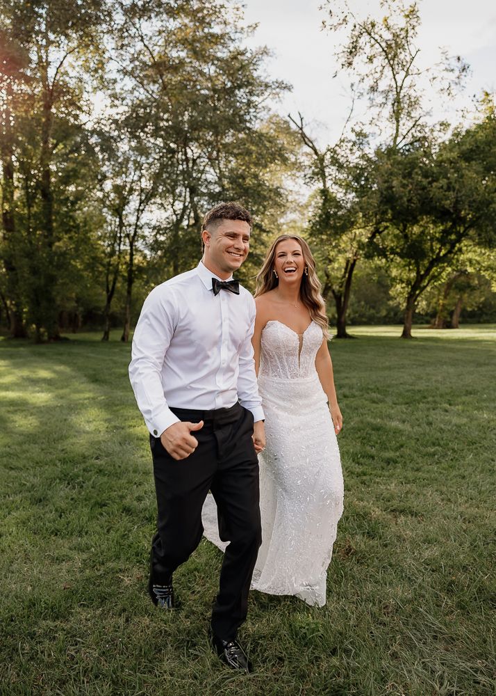 Couple poses together in a grassy field during golden hour.