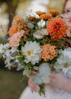 Wedding bouquet featuring coral dahlias, white daisies and peach roses.