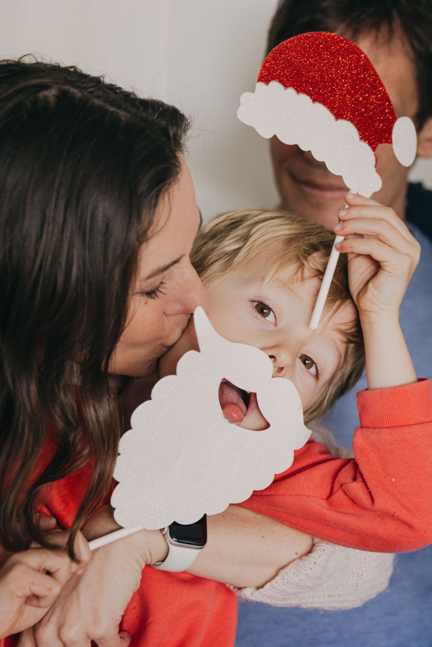 Une maman embrasse son petit garçon, qui porte une barbe et un bonnet de Père Noël, lors d'une session photo de Noël à Asnières