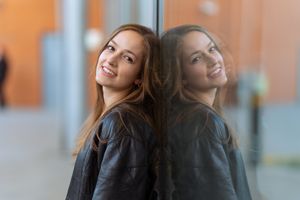 Two women laughing and posing against orange wall background in professional headshot series.