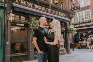 A couple in black clothing shares a romantic moment outside The Blue Posts pub in London.