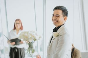 A joyful wedding ceremony in a bright indoor venue with white flowers and elegant decor.