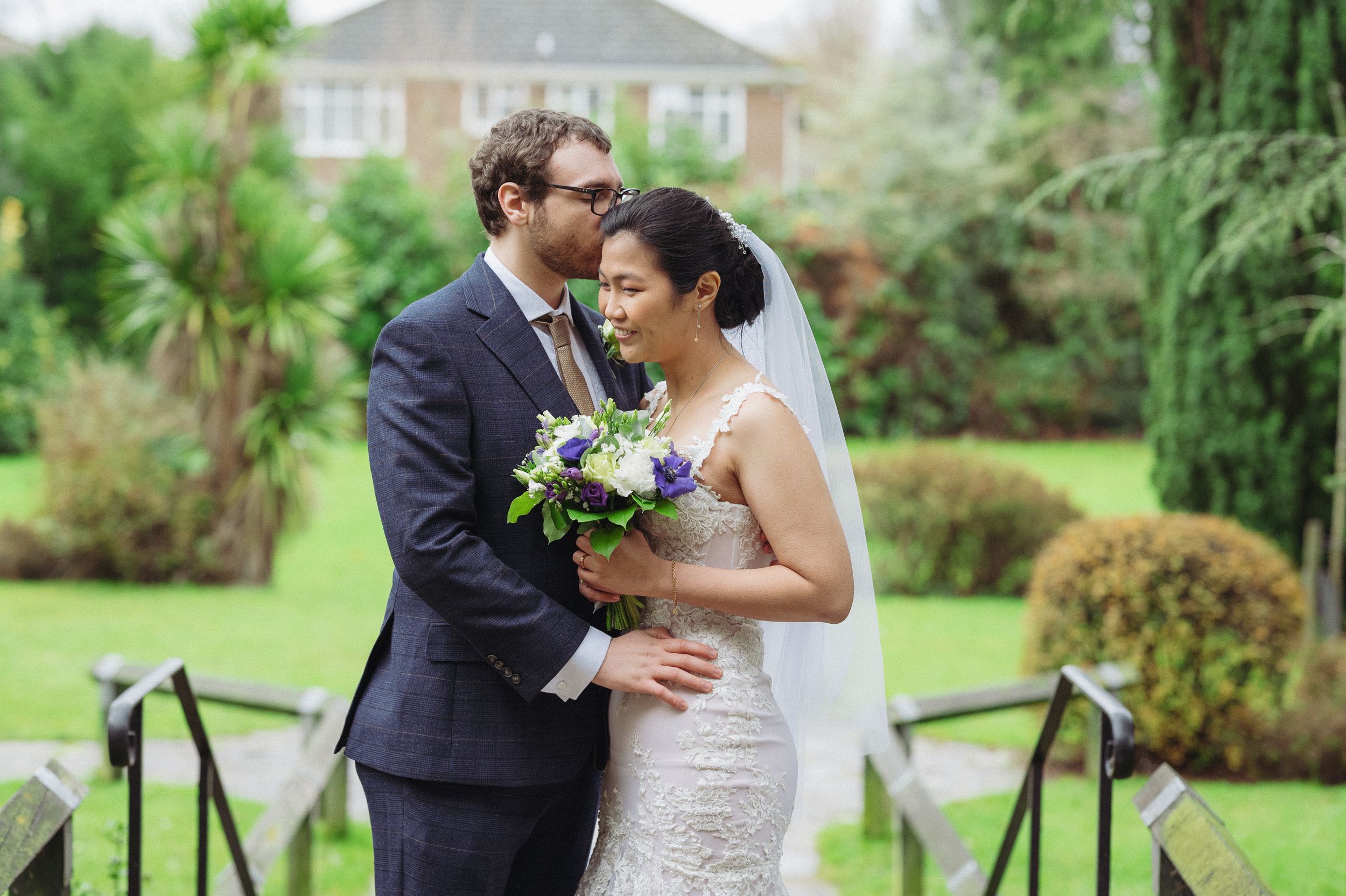 Tender moment between newlyweds posing in a garden with traditional bridal attire.