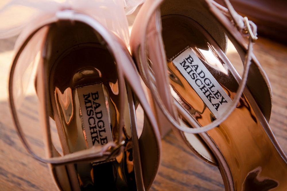 Close up of label tags inside pair of Badgley Mischka designer shoes on wooden surface.
