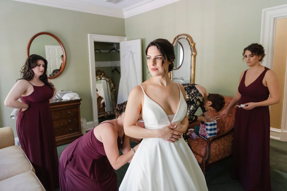 Wedding preparations take place in an elegant room with vintage decor and mirrors as a bride in white gets ready.