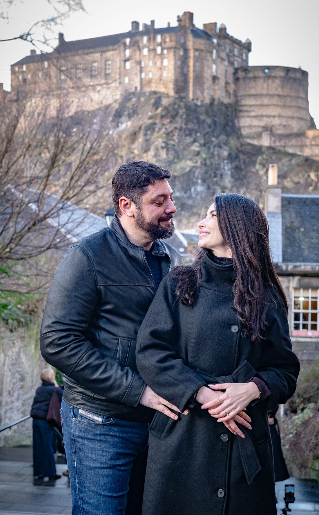happy couple on a wee scotia tour from Brazil looking at each other at the top of the stairs in the Grassmarket with Edinburgh Castle behind