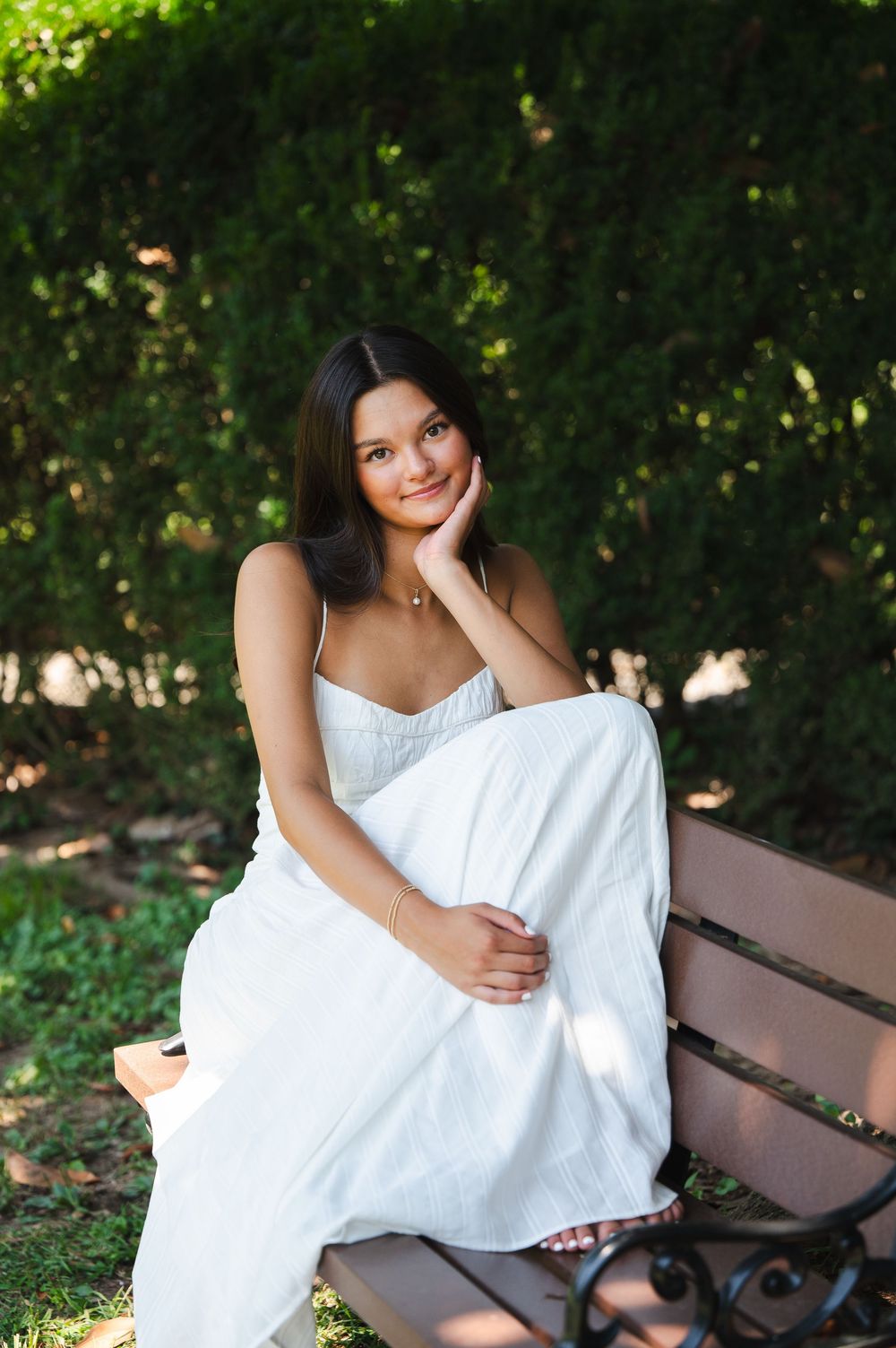 A series of outdoor portrait photos showing someone in a flowing white dress sitting on a wooden bench in a garden setting.