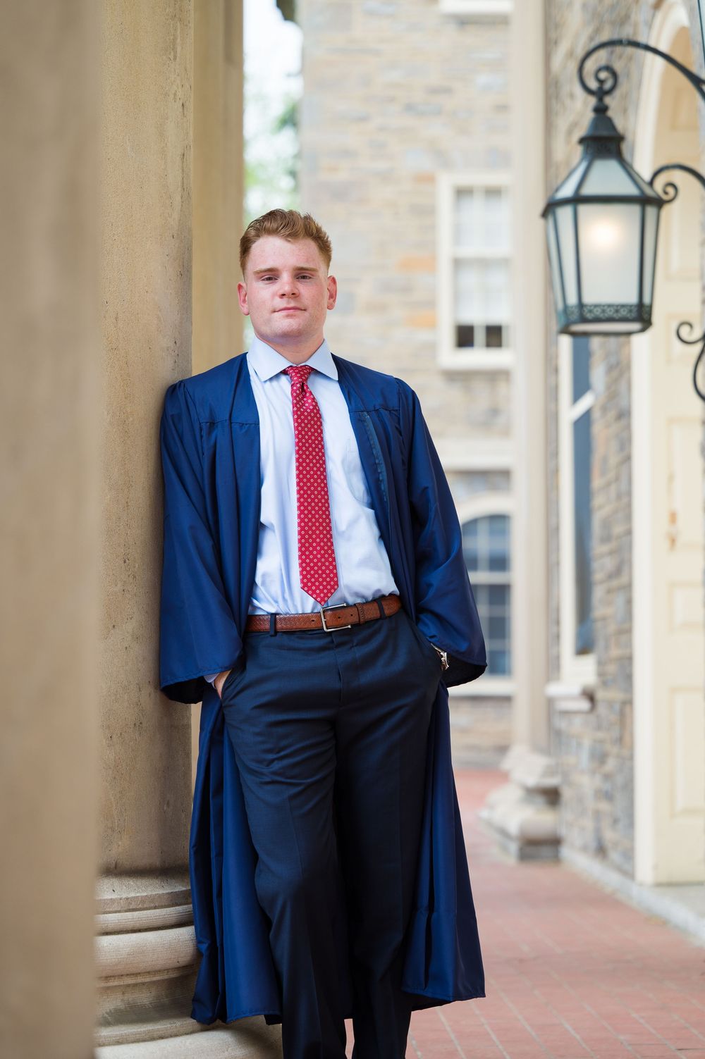Professional portrait series showing a person in a navy suit and red tie posing against a stone building exterior.