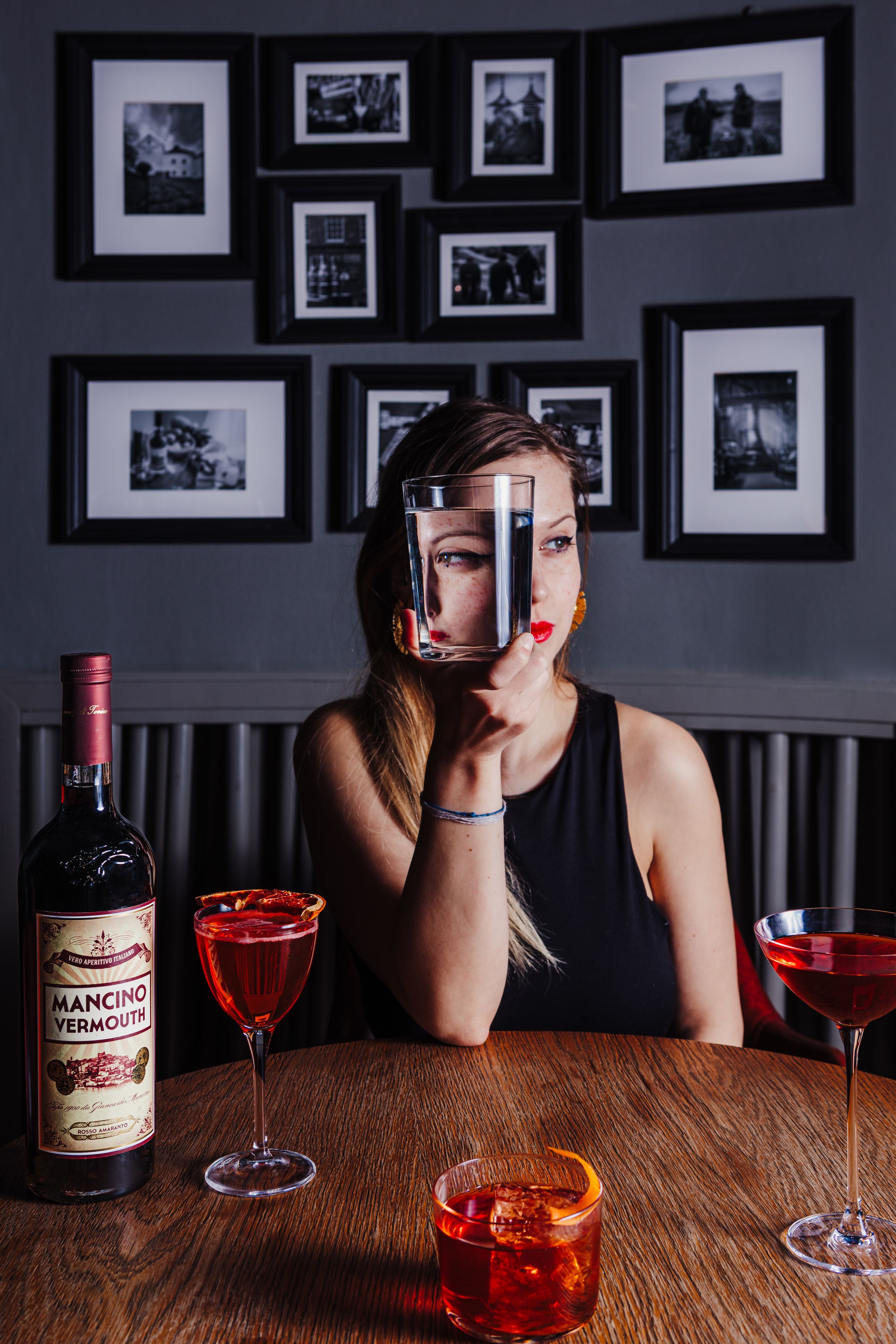 Creative cocktail photography with red drinks and framed wall art in background.