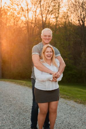 Happy couple embracing and laughing during sunset on a gravel path.