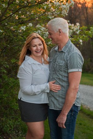 Couple sharing joyful moment under blooming dogwood trees at sunset.