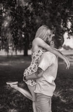 A romantic black and white photo of a couple embracing in a park setting.
