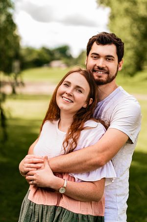 Joyful couple smiling and hugging in a green park during a sunny day.