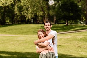 Happy couple embracing and laughing together in a sunny park setting.