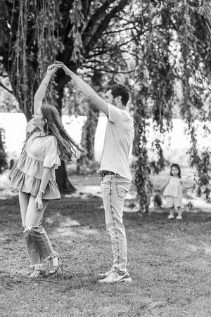 Couple dancing together under willow trees in black and white photography.