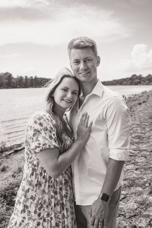 A couple poses together on a rocky beach during a romantic engagement photo session with the ocean in the background.