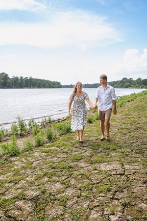 A couple explores a rocky shoreline together on a bright summer day.