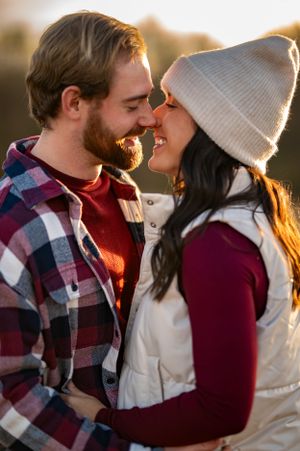 A cozy winter couple shares an intimate moment while wearing knit hats and plaid flannel.