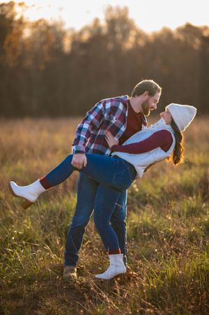 A playful couple dances and dips in a sunlit meadow during golden hour.
