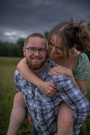 Couple embracing and laughing together in a grassy field during golden hour.
