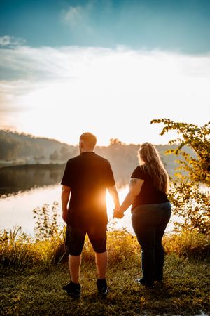 Silhouetted figures walk along a hilltop at sunset with golden light streaming through trees and foliage.