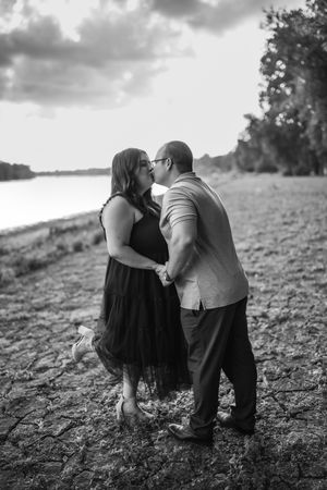A romantic black and white photo series showing a couple embracing on a grassy riverbank in four sequential frames.