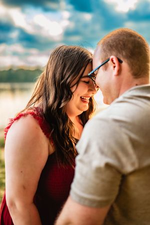 An intimate shot of a couple sharing a tender moment against a bright sky background.