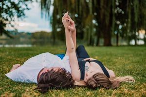 A person lies peacefully on green grass in a park setting during a sunny day.