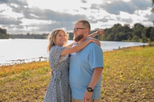 Couple embraces in a sunlit field during an autumn engagement photoshoot.