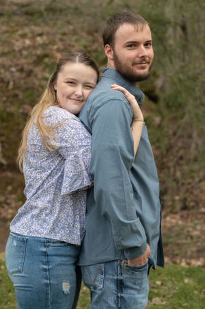 Playful couple in matching denim and floral outfits poses back-to-back outdoors.