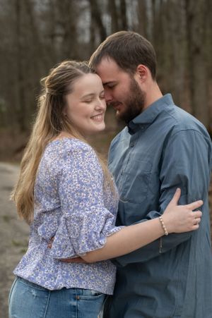 Couple in coordinated blue outfits shares intimate embrace during outdoor photoshoot.