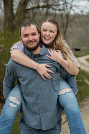 Joyful couple in blue outfits hugging and laughing during outdoor photoshoot.