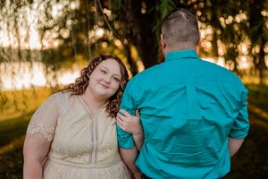 Two people pose together during golden hour sunset in a park wearing turquoise and cream colored outfits.