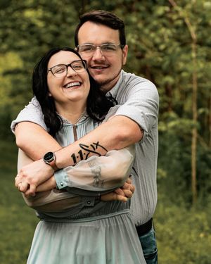 Joyful couple embracing and laughing together in a wooded outdoor setting.