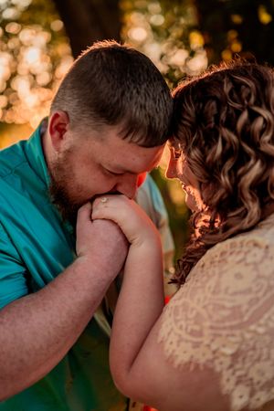 A tender romantic moment captured at sunset with golden bokeh lighting in the background.
