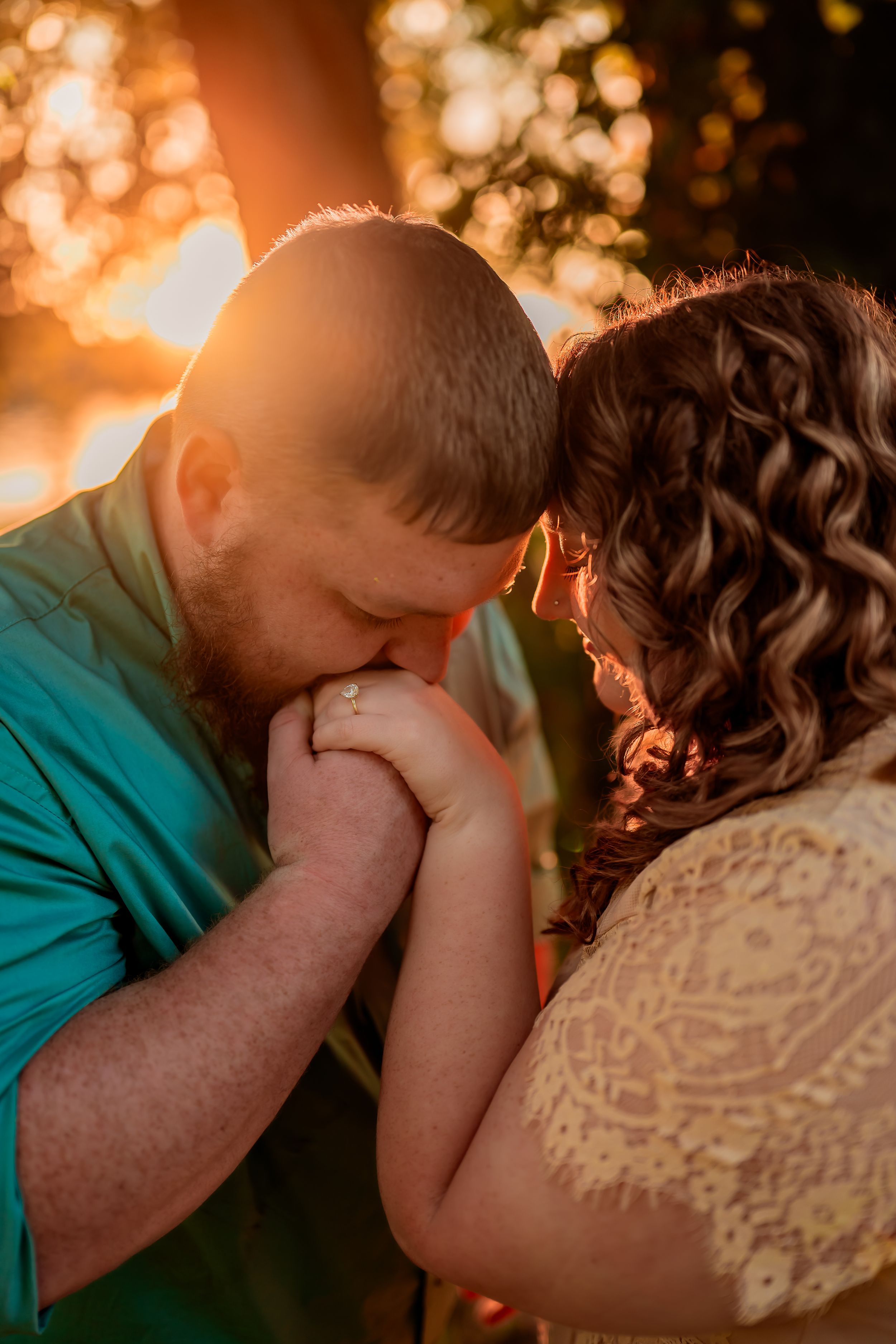 A romantic couple shares an intimate moment at sunset with warm golden bokeh lighting in the background.