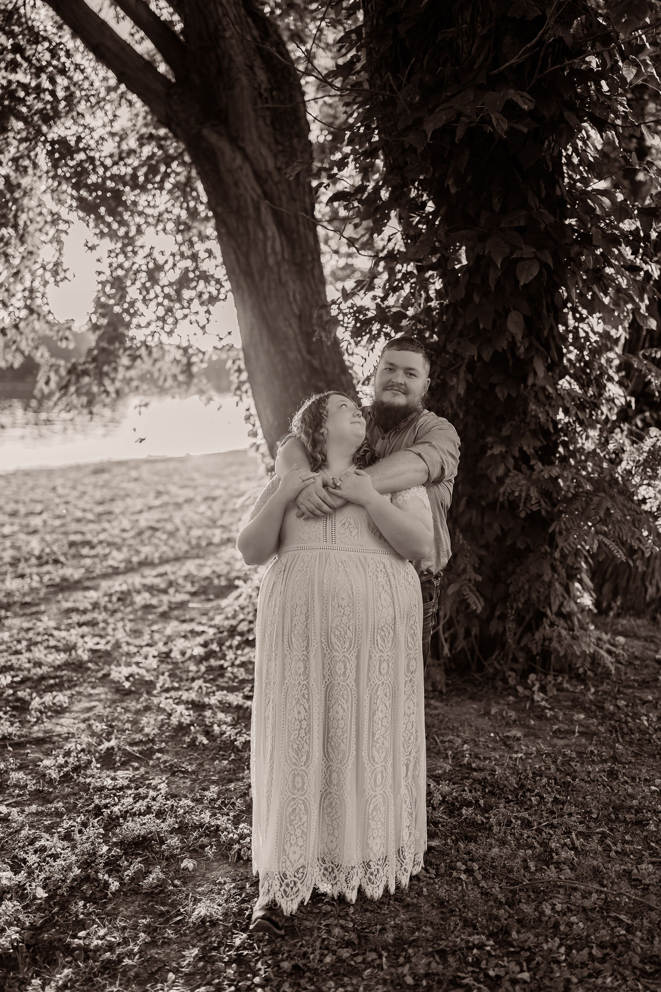 A series of black and white photos shows someone in a lace dress standing beneath a large tree in nature.
