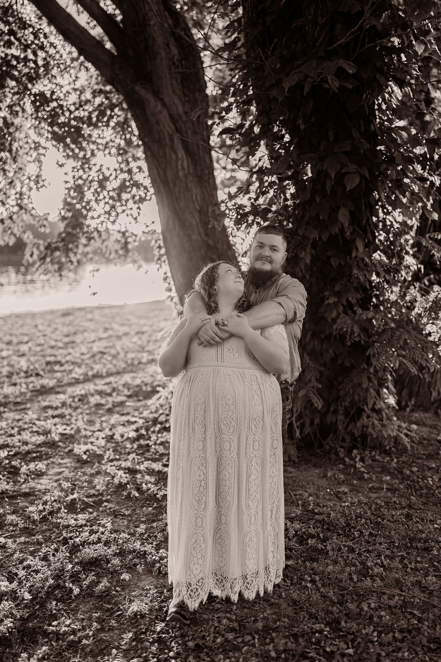 A series of black and white photos shows someone in a lace dress standing beneath a large tree in nature.