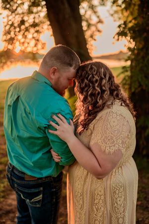 Four sequential photos of a couple embracing at sunset with golden light filtering through trees in the background.