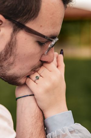 Close-up shot of engagement ring as couple shares intimate moment outdoors.