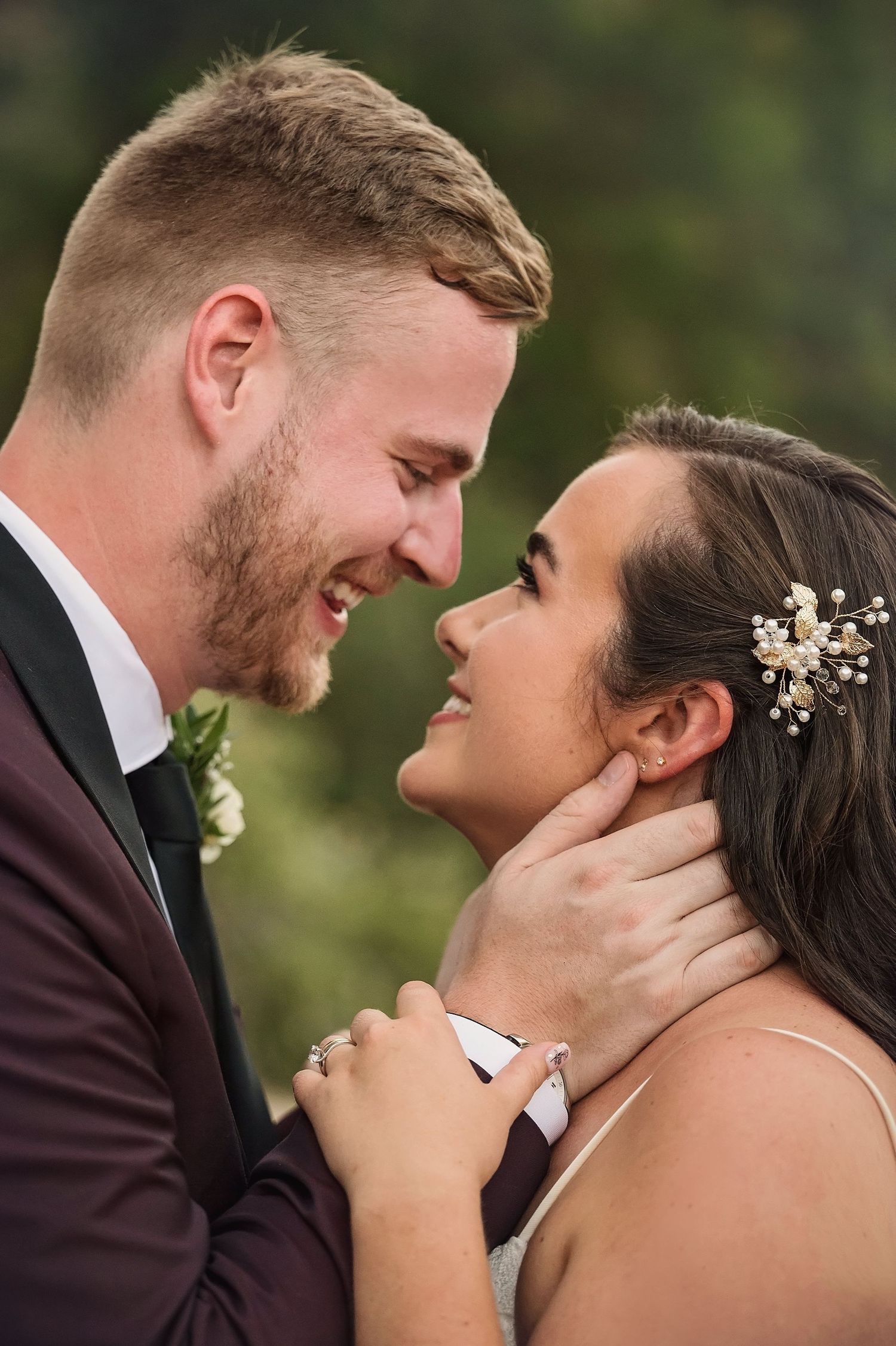 An intimate wedding portrait showing tender affection between newlyweds outdoors.