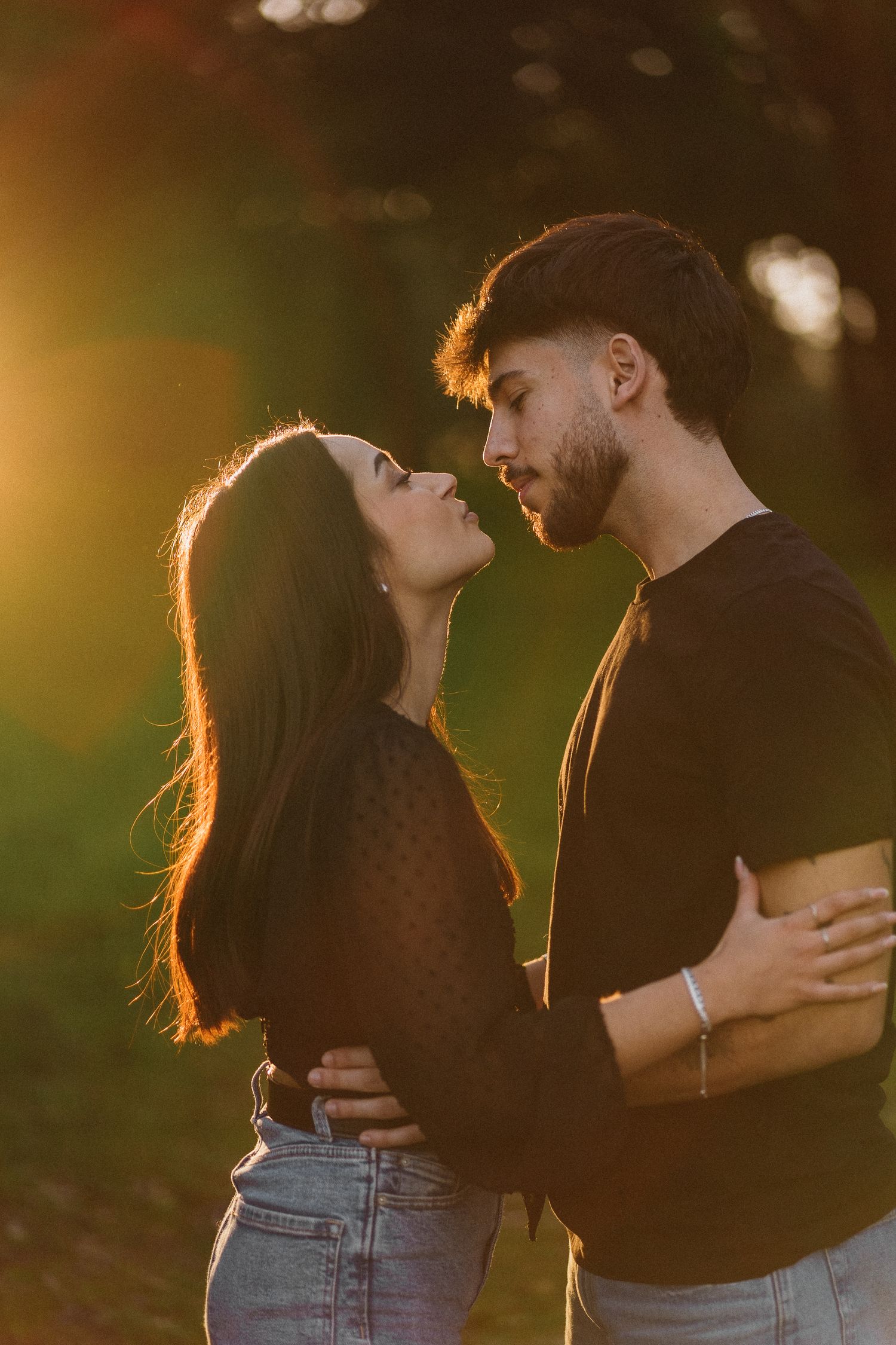 Close-up shot of a couple embracing outdoors with blurred nature background.