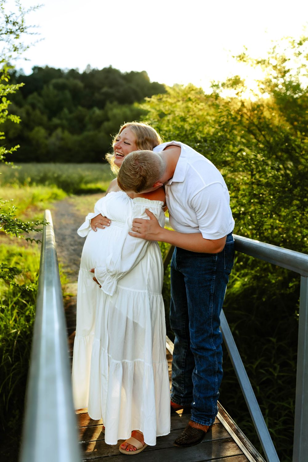 A romantic couple shares an intimate moment leaning against a metal railing at sunset in a garden setting.