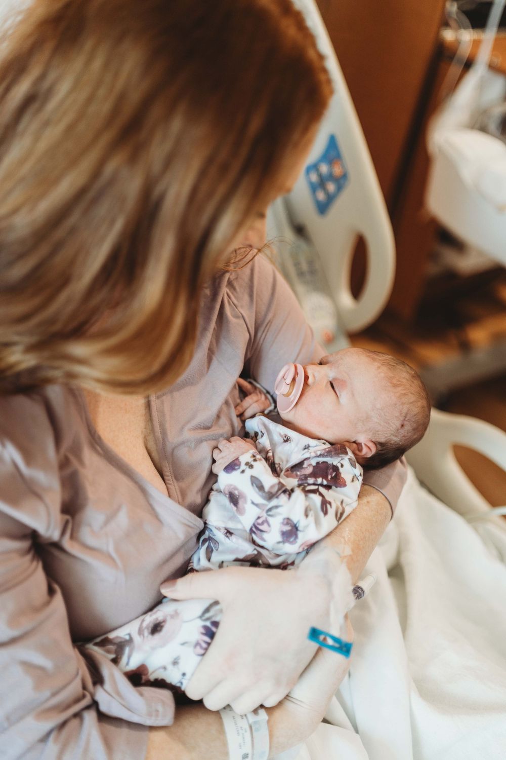 Tender moment between parent and sleeping newborn in hospital setting.